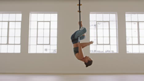 aerial yoga woman practicing inverted butterfly pose hanging upside down using hammock enjoying healthy fitness lifestyle exercising in studio training meditation at sunrise