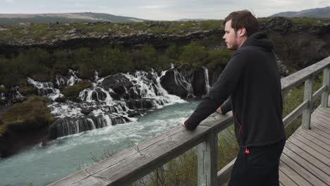 在冰島的巴納福斯<unk>布 (barnafoss waterfall) 欣賞美景的英俊年輕男性是肖像