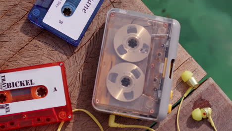 cassette tape record player vintage old school music release playing on wooden pier with water in background and bright colour