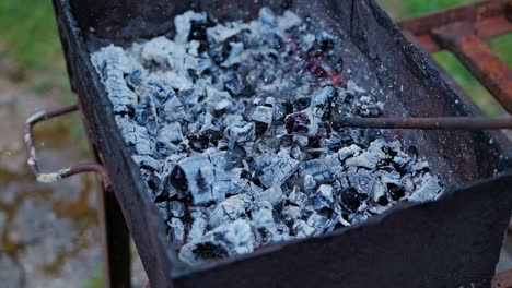 slow motion reveals sparks and glowing embers as iron rod stirs coal in fire pit