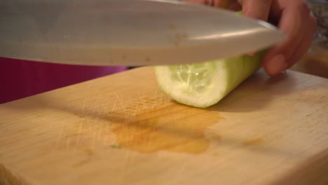 A-cucumber-on-a-cutting-board,-slowly-sliced