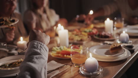 a large family has a festive dinner in honor of thanksgiving, they sit at the festive table with delicious food