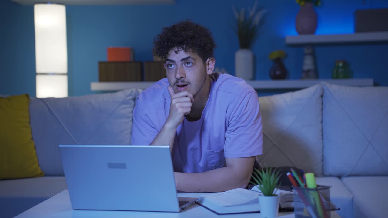 Confused and panicked young man looking at laptop at night.