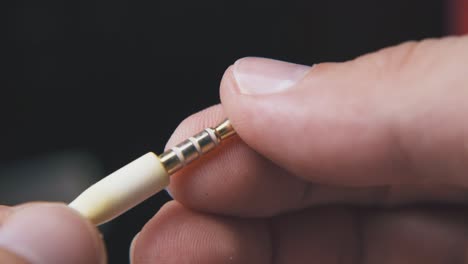 person-touches-jack-plug-with-cable-on-black-background