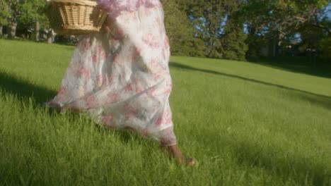 Lovely-black-lady-with-dress-and-picnic-basket-walks-barefoot-over-grass