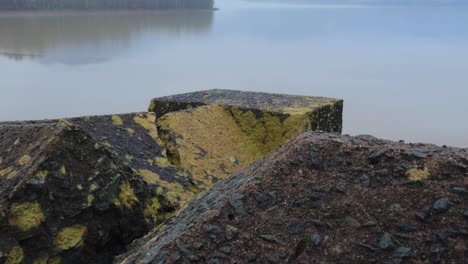 ancient stone wall in front of a placid, beautiful mountain lake on a foggy mysterious day