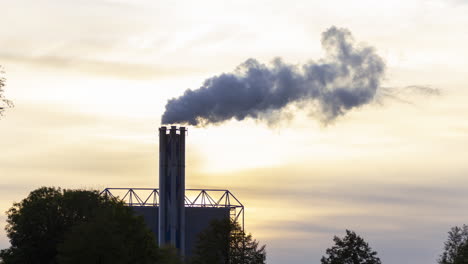 Time-lapse-of-smoking-factory-chimney-against-the-background-of-a-setting-sun---slow-zoom-in