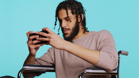 man in wheelchair playing videogames on cellphone, celebrating victory, studio