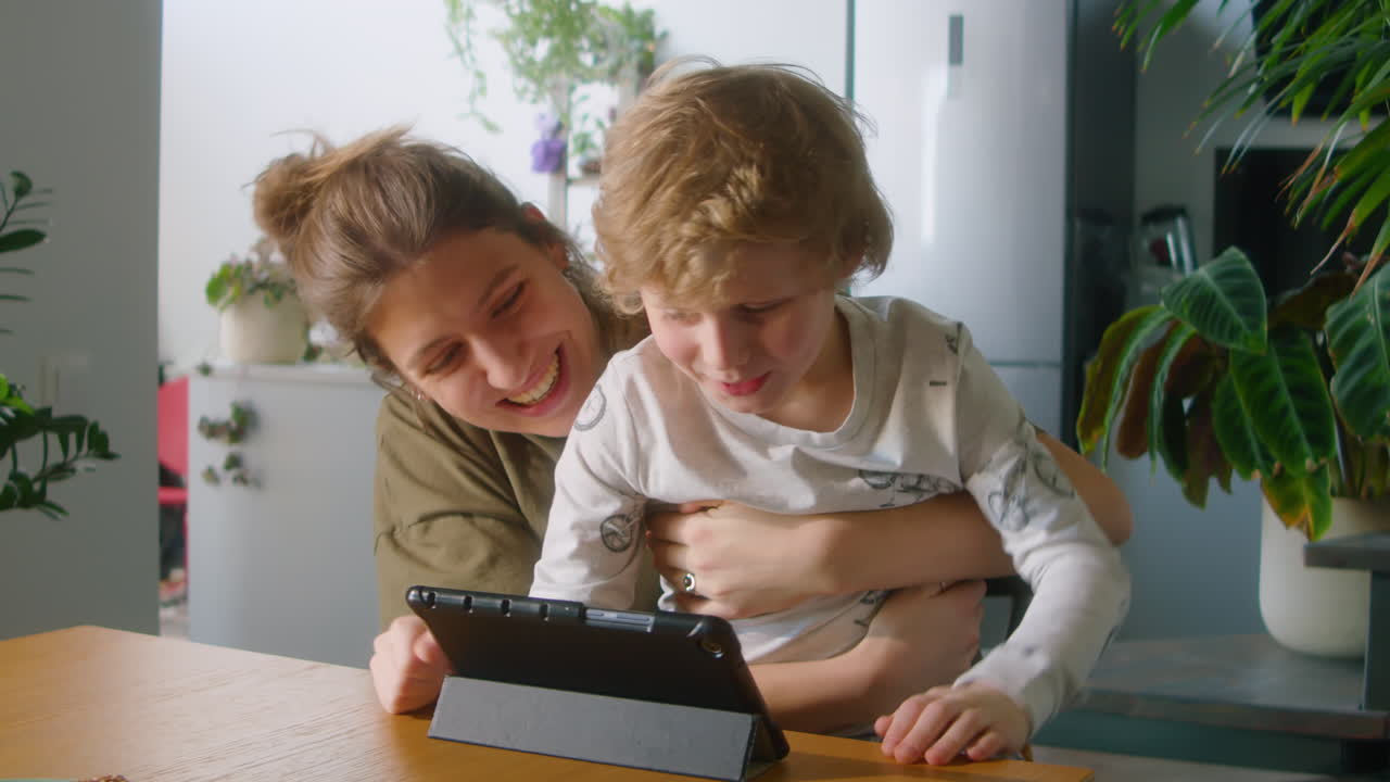 Excited Mother and Kid Playing on Digital Tablet at Home