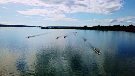 aerial view of a rowing competition between several teams, with clear sky and clouds reflecting on the waters