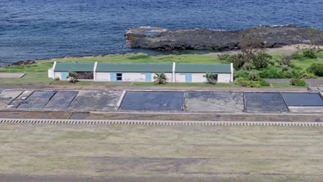 Drone-view-with-long-focal-length-hovering-over-the-salt-pan-and-salt-barn-of-Pointe-au-Sel-in-Saint-Leu,-Reunion-Island,-with-an-orbit-movement