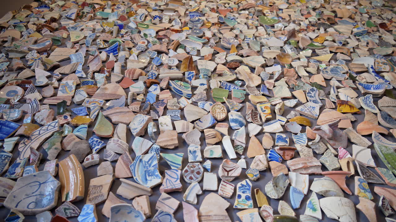 Alicante, Spain - May 26, 2025: Dense field of colourful glazed sherds arranged on a tabletop inside MACA