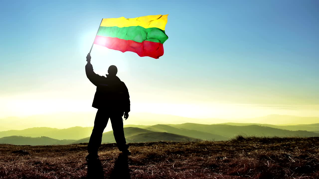hombre ganador de silueta exitosa agitando la bandera de lituania en la cima de la montaña, fondo de bucle de cinemagraph
