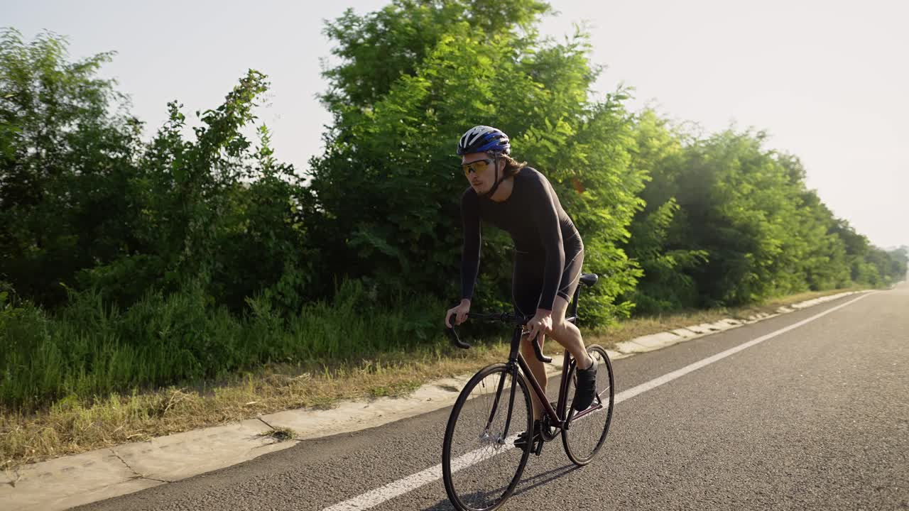 Ciclista professionista uomo con il casco pedala lungo una pista vuota.