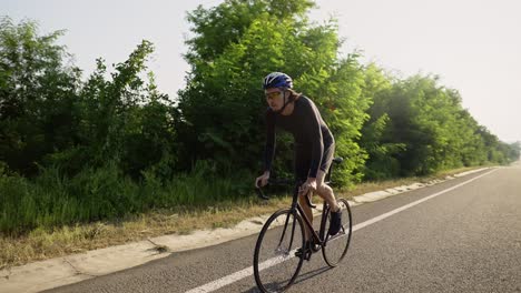 professional male cyclist in helmet rides bicycle along and empty track