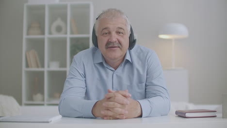 adult man is communicating online looking at camera and using headphones concept of video call or webinar