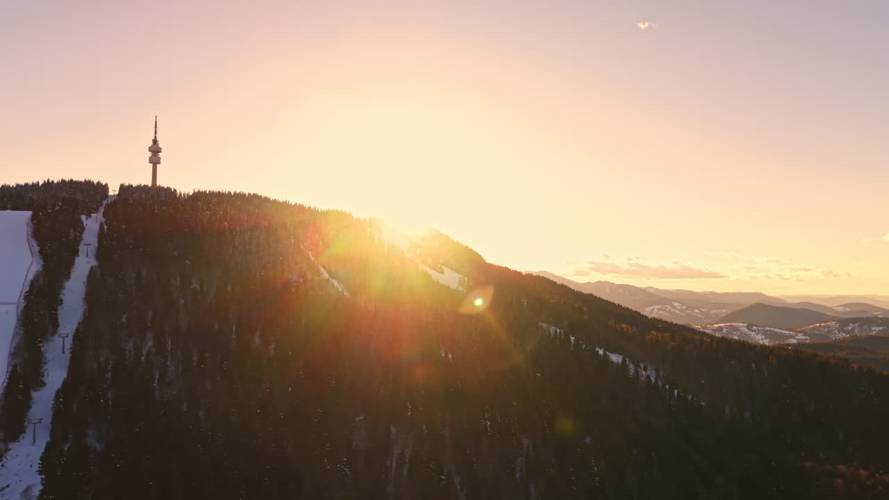 Sunrise over the mountain with a tower and snow covering the ground in a winter landscape, capturing the beauty of nature and changing light