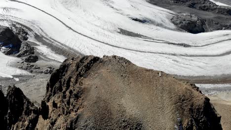 Aerial-flyover-over-Fuorcla-Trovat-peak-at-Diavolezza-in-Engadin,-Switzerland-with-a-pan-up-revealing-Pers-glacier-and-other-peaks-of-the-Swiss-Alps-around-St