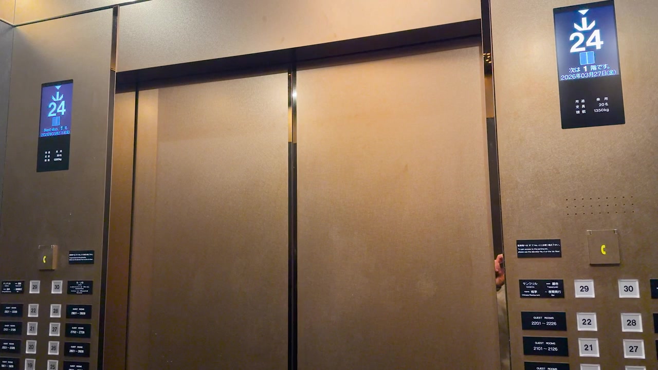 Static shot of metallic elevator doors and digital screen showing floor numbers descending in Japan.