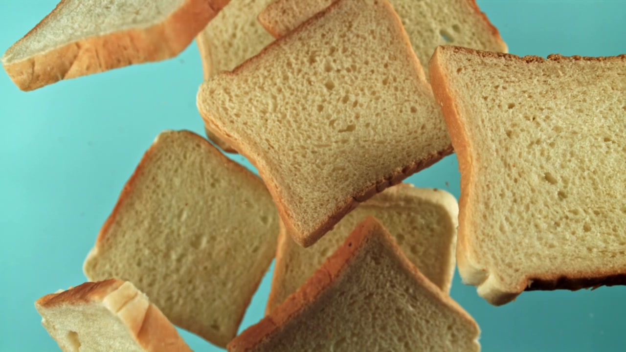 Slices of White Bread Falling in Slow Motion on Blue Background