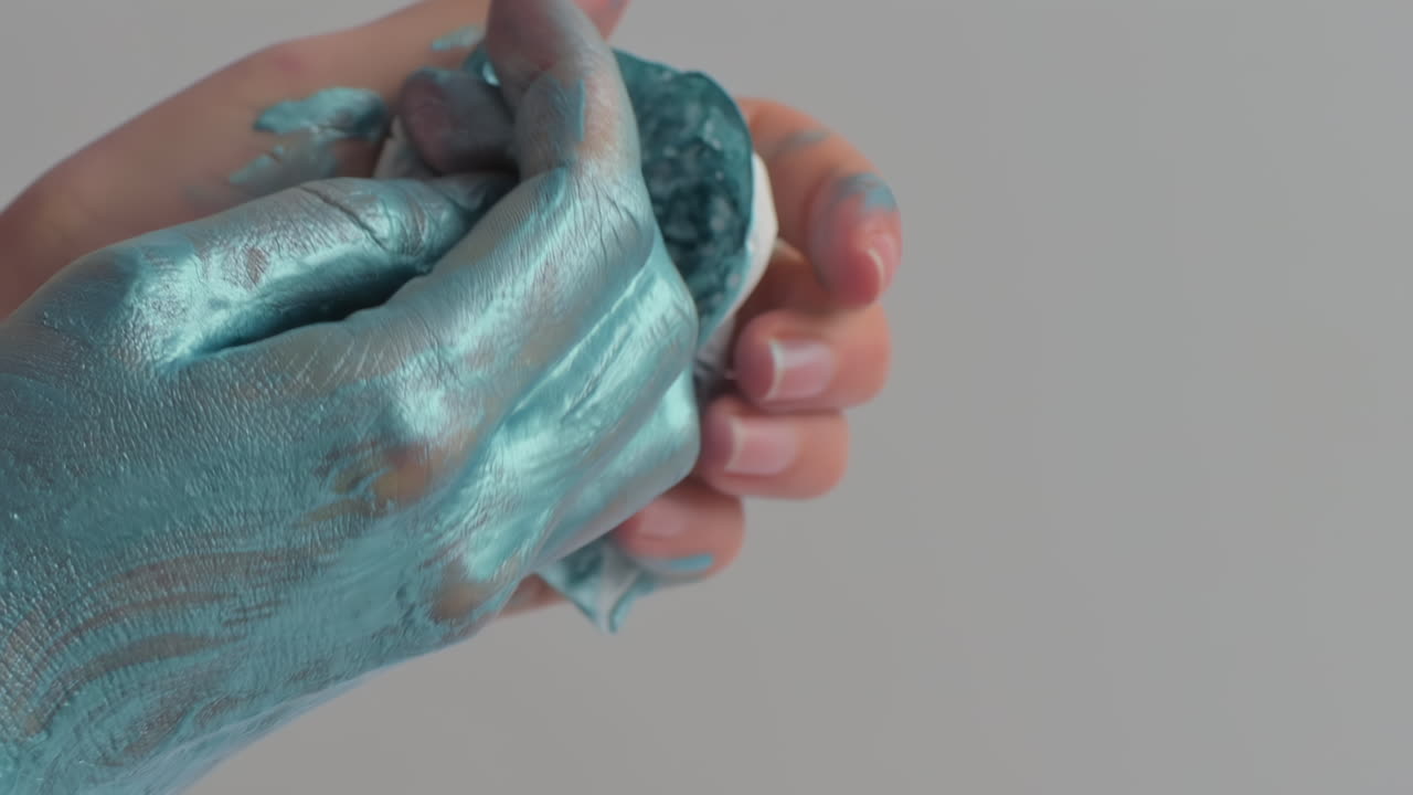 Hands are covered in blue paint, creating interesting textures and patterns. This activity takes place in an art studio, showcasing fun and engaging ways to explore creativity