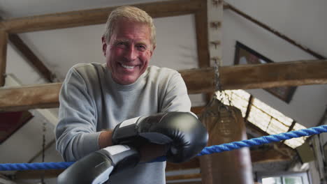 portrait of senior male boxing coach in gym standing in boxing ring