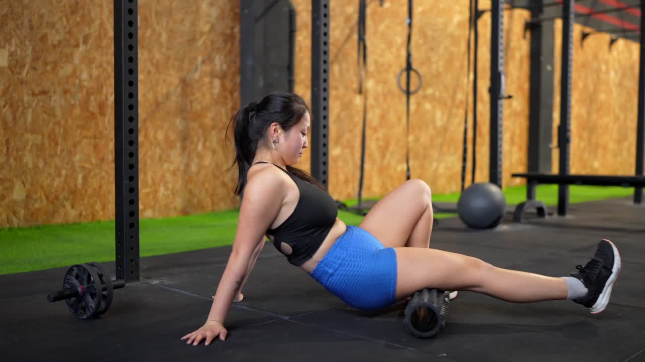 Woman using foam roller for muscle recovery in the gym
