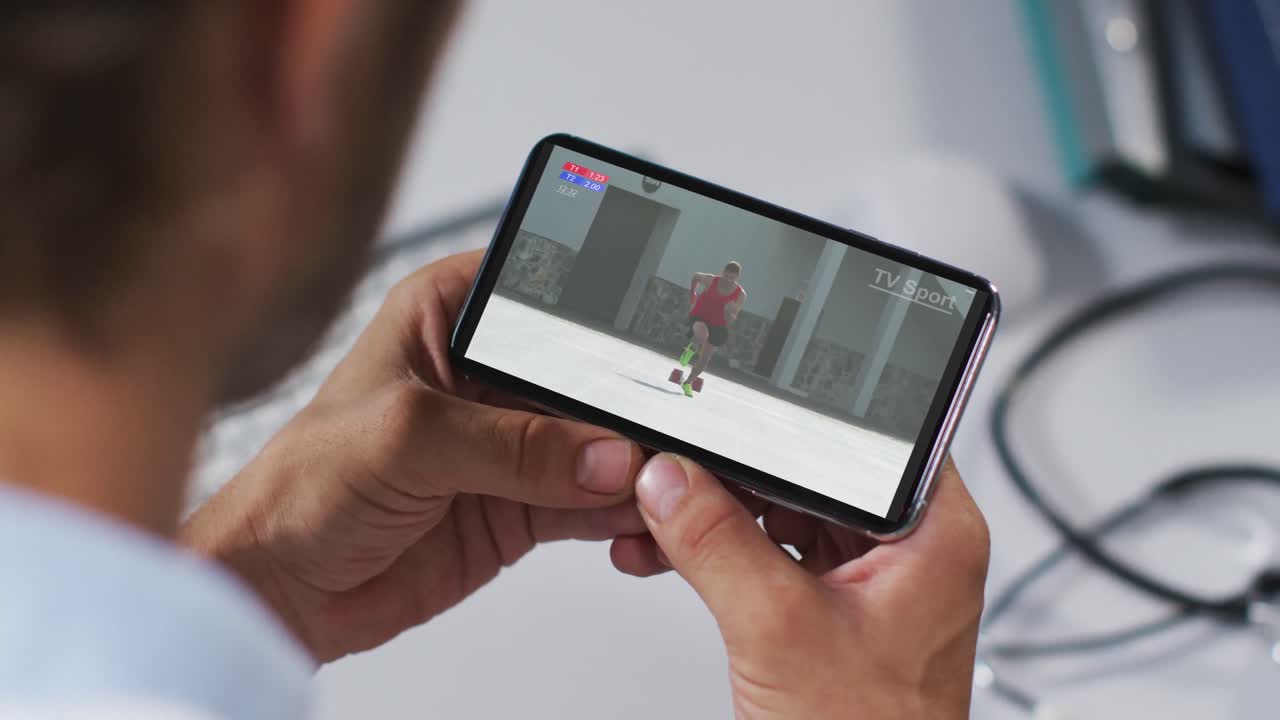 compuesto de un médico masculino viendo un evento de atletismo en un teléfono inteligente