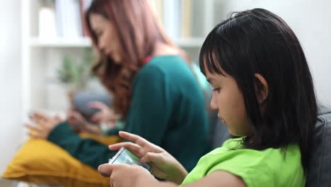 young asian girl and her mother using smartphone in living room at home