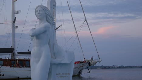white statue of a woman near a yacht at sunset