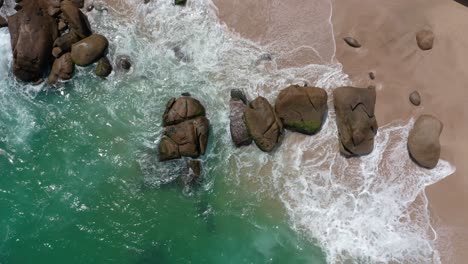 Vista-De-Arriba-Hacia-Abajo-De-Hermosas-Rocas-En-La-Playa-Junto-Al-Mar-Con-Olas-Rompiendo