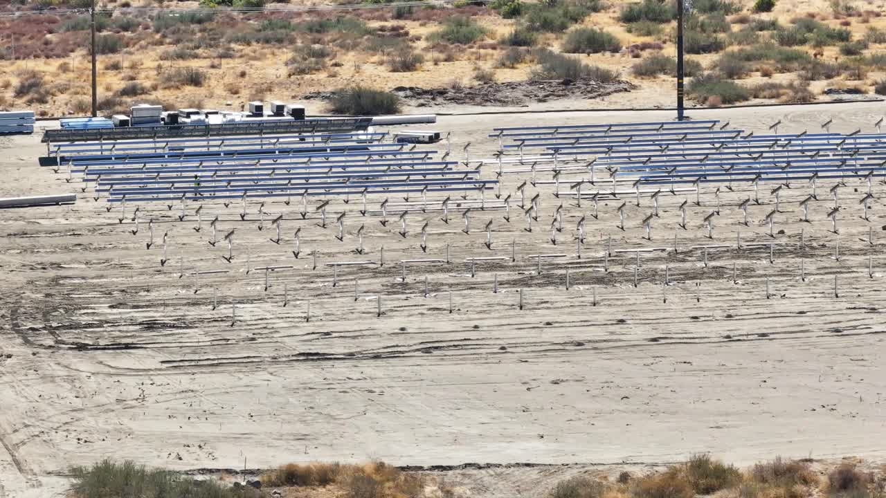 trabajador caminando a través de una serie de marcos de paneles solares en un sitio de construcción en el desierto tiro estático
