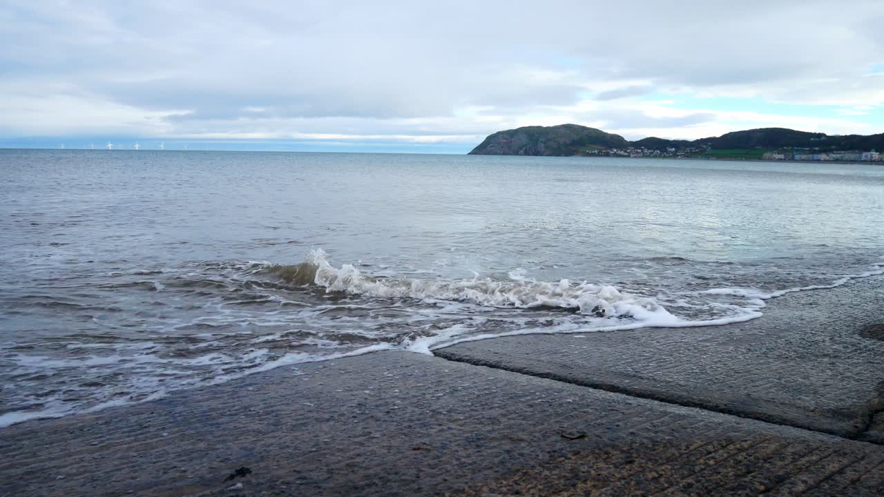 흐린 바다 해안선으로 이어지는 콘크리트 부두 상륙을 씻는 파도 돌리 왼쪽