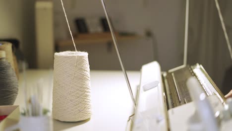 female hands weaving fabric on knitting machine in workshop