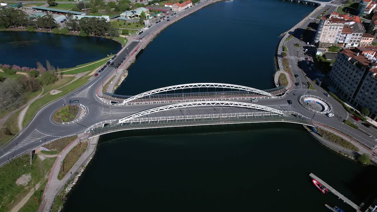 Overhead drone push in on Puente de As Correntes road bridge over the Lérez River in Pontevedra, Galicia, Spain with vehicles crossing waters