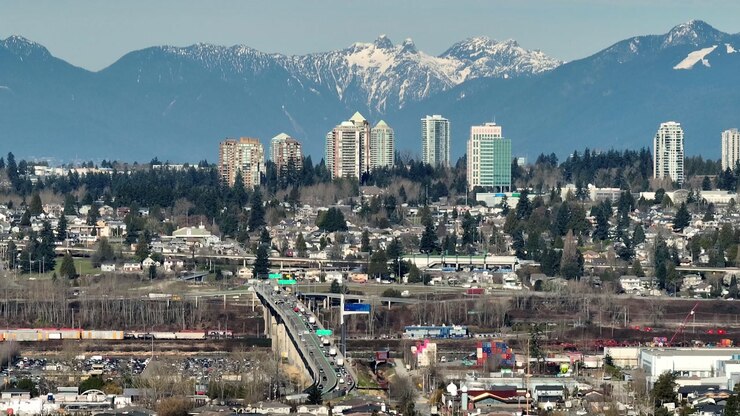 Queensborough Bridge In New Westminster, Canada, With Burnaby Skyline And North Shore Mountains In Background. aerial tilt-up shot