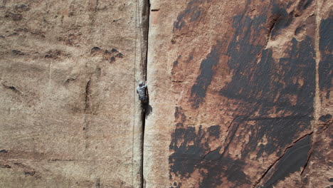 aerial view of climber, ropes and crack in steep sandstone cliff, extreme sport drone shot