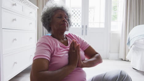 senior african american woman practicing yoga in bedroom at home