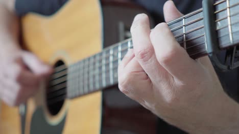 vista lateral de un guitarrista tocando fingerstyle en una guitarra acústica de cuerdas de acero