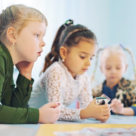 curious girls at the table at school. three mobile kids leaning on the table during the lesson. elementary school. close-up.