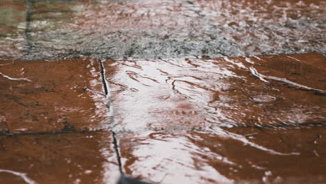 heavy rain falling on red pavement