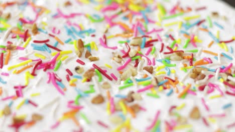 cake adorned with icing, sprinkles and chopped walnuts