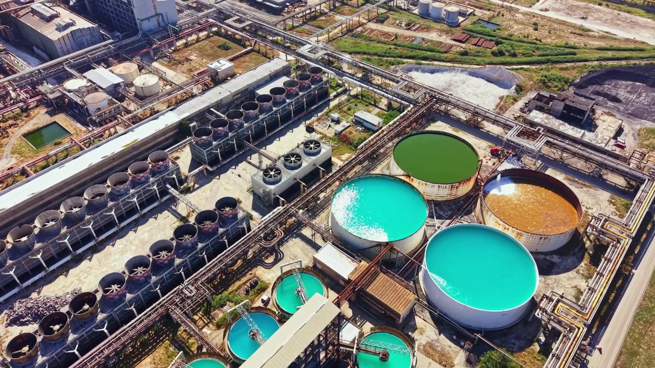 Industrial site shows large tanks and pipelines for processing materials in a complex setup during daylight hours
