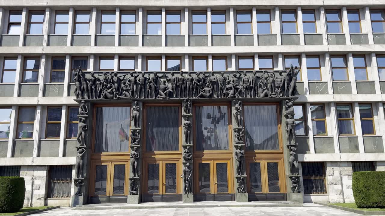 Front view of the National Assembly Building Of Slovenia in Ljubljana, featuring the large oak doors, many iconic statues and modernist architecture