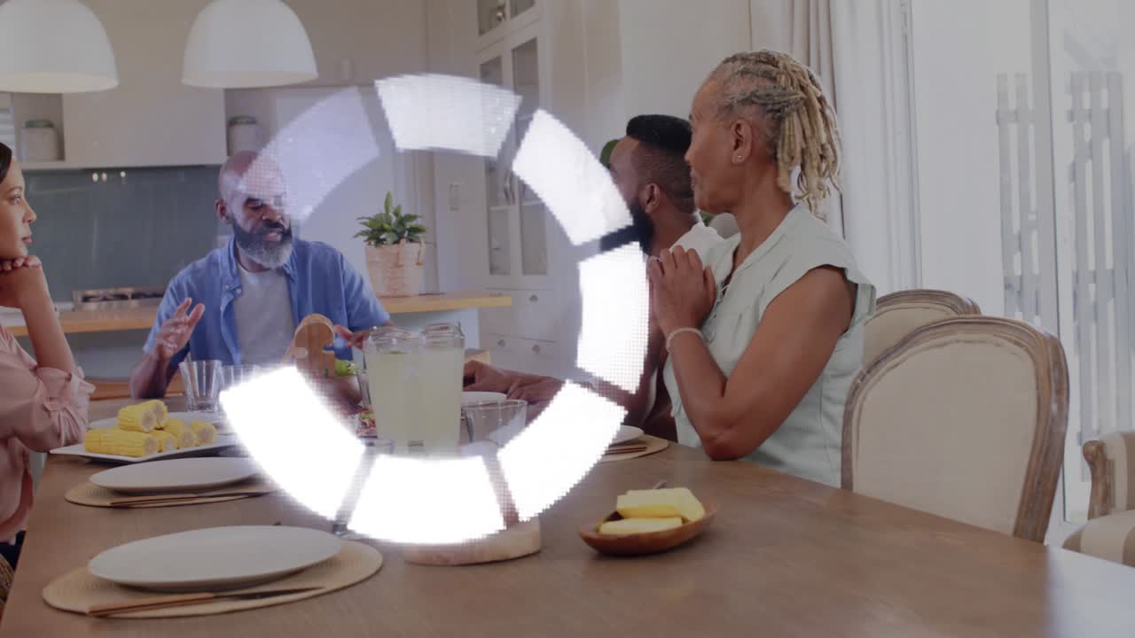 Family holding hands bowing before food, rotating circular overlay obscuring center while passing