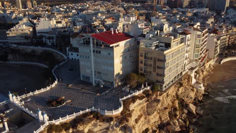 Aerial-descent-focusing-on-cape-of-Benidorm-typical-coastal-building-apartments-at-sunset-time