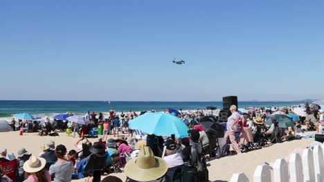 crowded beach event with a helicopter passing overhead