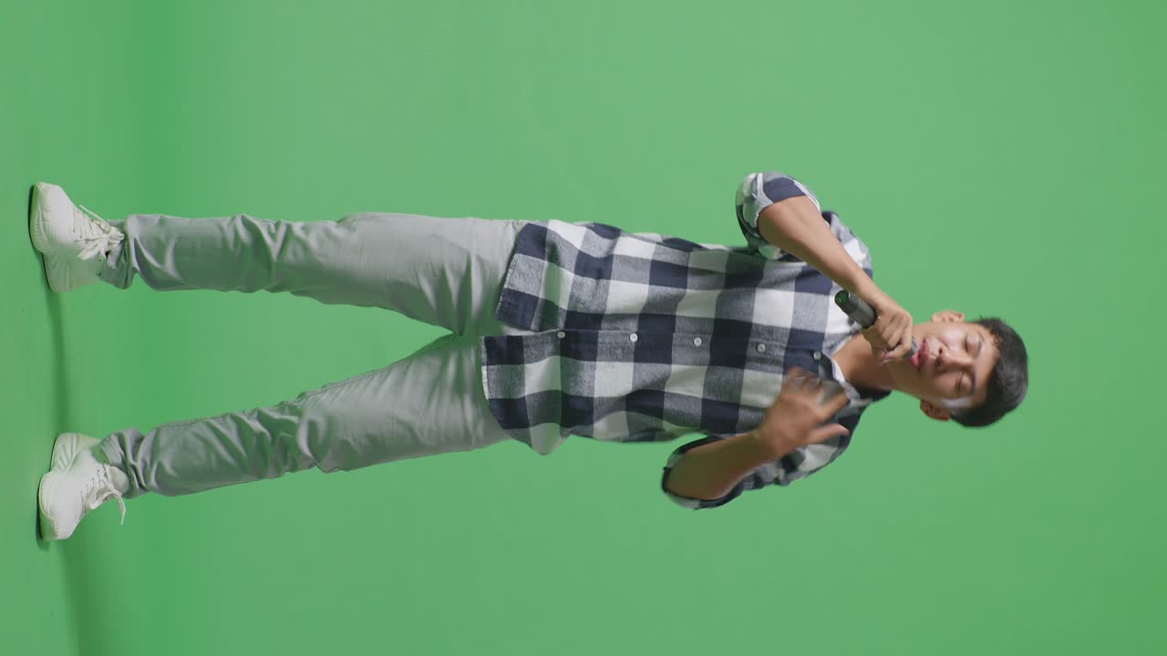 Full Body Of Young Asian Teen Boy Holding A Microphone And Rapping On The The Green Screen Background