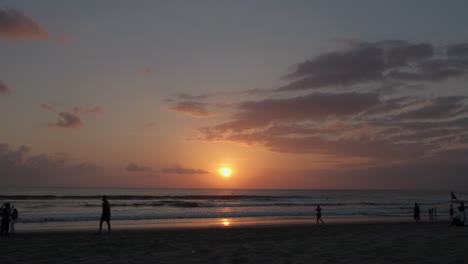 kuta playa puesta de sol con gente caminando silueta nubes cielo arena y mar