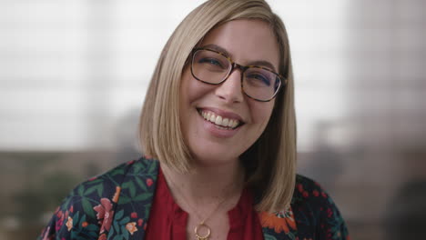 close up portrait of friendly blonde business woman laughing cheerful looking at camera wearing glasses in office workplace background